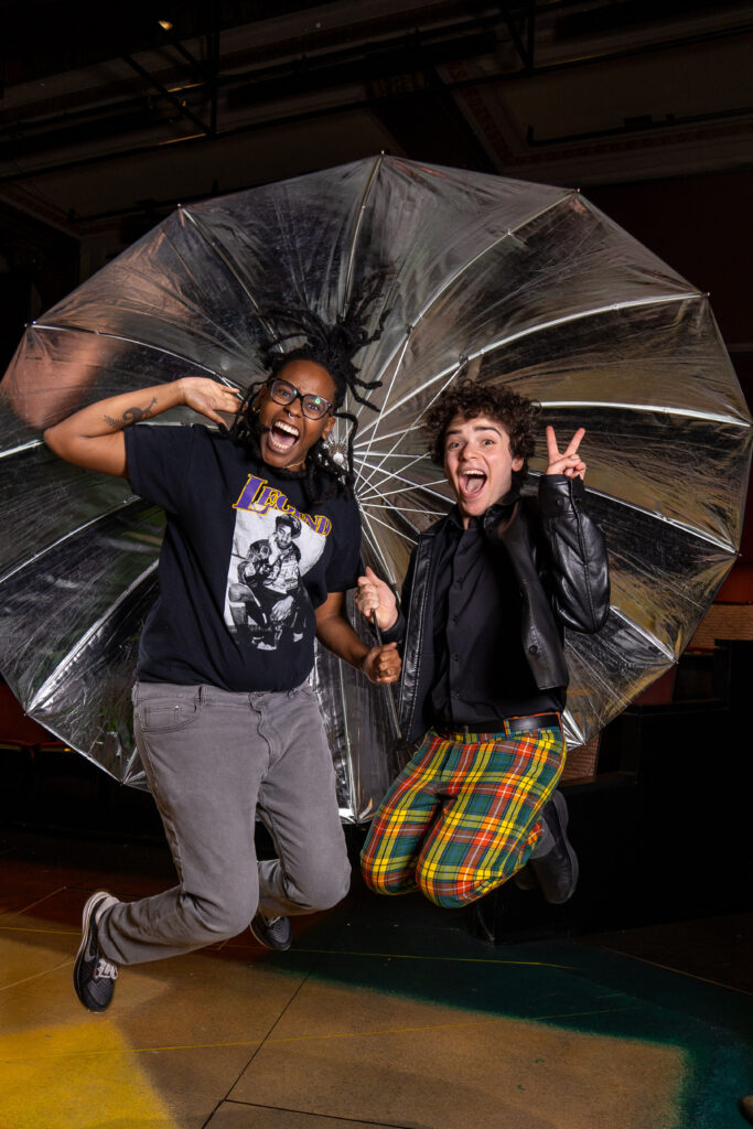 Behind-the-scenes moment: Photographer and senior boy, Hersh from Seattle Academy of Arts, jumping high in the air during his senior photo session in a theater in Everett.