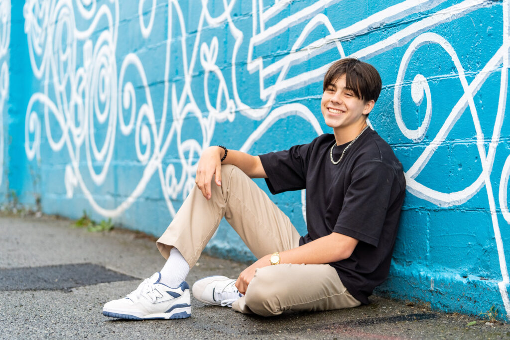 Portrait of a senior boy, smiling confidently in downtown Edmonds, captured by a senior photographer for son in Everett.