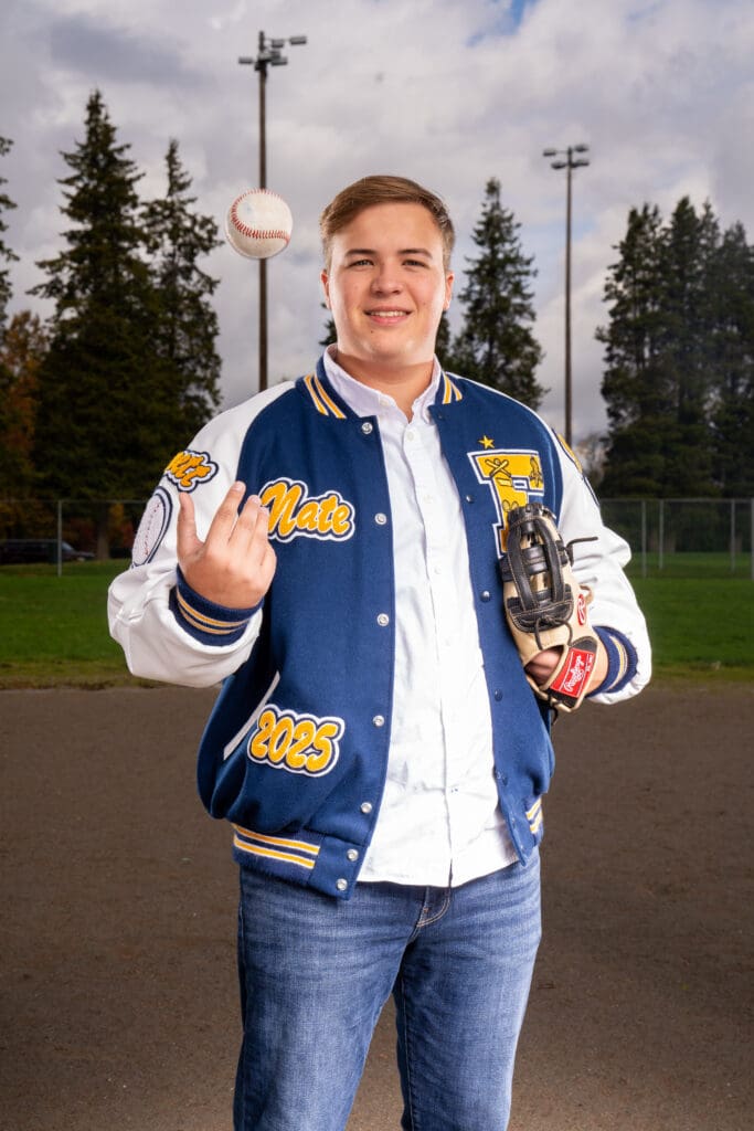 Senior baseball player posing on the field with bat and glove in Issaquah senior photoshoot.